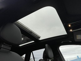 【パノラミックライディングルーフ】紫外線を効果的に遮るUVカットガラスを採用し、ウインドデフレクターも装備しています。ワンタッチ開閉機能、挟み込み防止装置も備わります。後部座席のガラスは開閉しません。