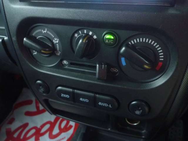 エアコン操作部です。現行モデルはオートエアコンですがJB23Wはマニュアルエアコンとなります。その下部には4WD切り替えスイッチとミラーヒーター＆シートヒータースイッチがございます。