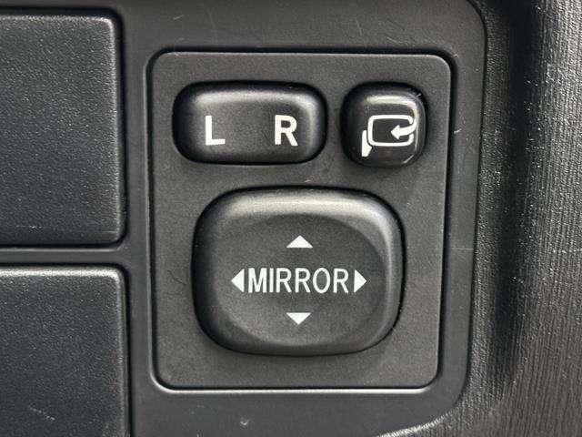 電動格納ミラーの操作スイッチですね。　駐車時にミラーを動かそうと外に出る必要も無く、悪天候の時でも運転席に居ながらミラーの操作できますよ。　一度使うと手放せない装備ですよね。