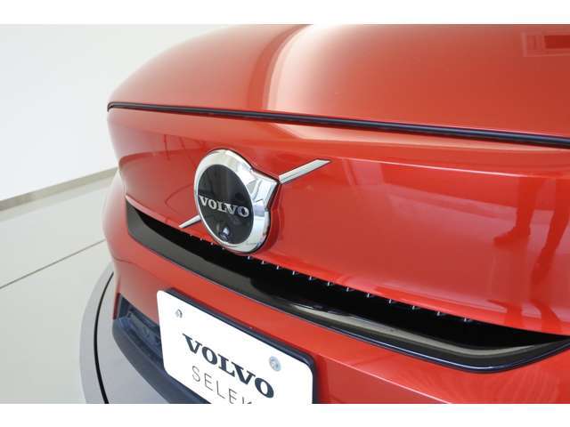 【ボルボの電気自動車を象徴するフロントフェイス】時代に合わせて変化するエンブレムデザイン。センターを斜めに大きく横切るラインと黒地に銀のアイアンマーク、これが最新ボルボのキャラクターアイコンです。