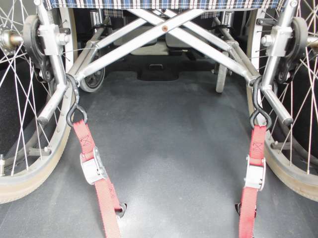 車いすの後ろ側を固定ベルトで留めて、前側からウィンチで引っ張って車いすを固定する仕組みです。