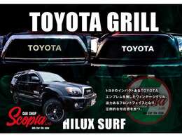 【当社のハイラックスサーフは新品フロントグリルを装着しております】トヨタのインパクトあるTOYOTAエンブレムを施したヴィンテージグリル。迫力あるフロントフェイスとなり、ひときわ目立った存在感を放つ。