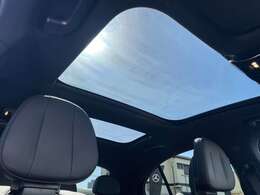 【パノラミックライディングルーフ】紫外線を効果的に遮るUVカットガラスを採用し、ウインドデフレクターも装備しています。ワンタッチ開閉機能、挟み込み防止装置も備わります。後部座席のガラスは開閉しません。