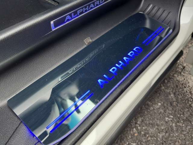 アルファードロゴ入りスカッフイルミネーションステップライト装着・ドアオープン時、運転席・助手席の足元で、車名ロゴがブルーのLED照明に美しく浮かび上がります