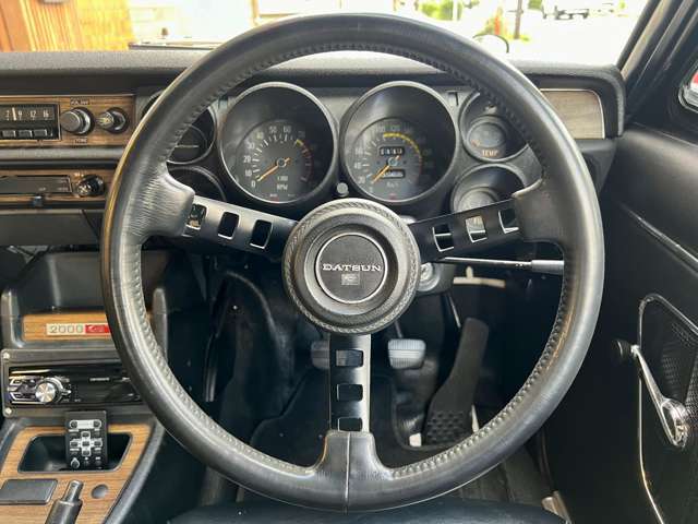 日産の旧車必須アイテムとも言える『DATSUNコンペステアリング』を装着し小径ステアリングでスポーティ◎純正標準設定のウッドパネルや2000GTロゴエンブレムが中央に鎮座！ヒーターとラジオはOP設定◎