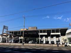 屋根付きの展示場（宇宿3丁目41-2）とAudiの看板が目印です。