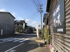 展示場から見た、当店の店舗への入り口です。ストレートの建物奥から左に入って頂きますと右手に青い店舗があります。